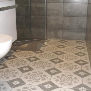 Ferdig bad. Grå fliser på vegger. Gulvfliser med mønster i hvitt og grått.