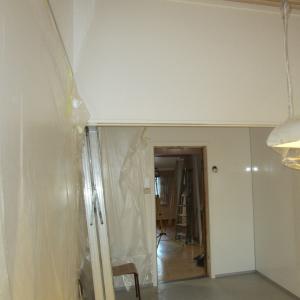 Kjøkkenrom med glatte hvite plater på alle vegger. Dør til naborom.