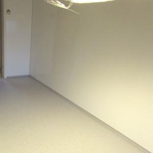 Kjøkkenrom med glatte hvite plater på alle vegger. Mot gulv med belegg.